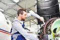 Aircraft mechanic repairs an aircraft engine in an airport hangar