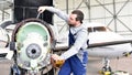 Aircraft mechanic repairs an aircraft engine in an airport hangar Royalty Free Stock Photo