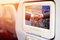 Monitor in front of passenger seat showing Business men shaking hands in businness background