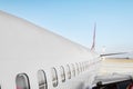 Aircraft porthole - side window airplain. White heavy passenger jet engine airplane on runway at airport against blue sky aviation Royalty Free Stock Photo