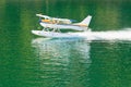 Aircraft seaplane taking off on calm water of lake Royalty Free Stock Photo