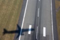 Aircraft shadow after takeoff on ground over airport runway with green grass Royalty Free Stock Photo