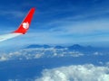 Aircraft wing with airline logo on air flying with background blue sky and and mountains view Royalty Free Stock Photo