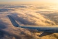 An aircraft wing banking over fluffy clouds as the sun begins to Royalty Free Stock Photo
