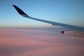 Aircraft wing blue sky with pink clouds below Royalty Free Stock Photo