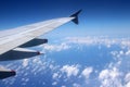 Aircraft wing blue sky, white fluffy clouds below Royalty Free Stock Photo