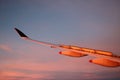 Aircraft wing flaps up blue sky pink clouds below