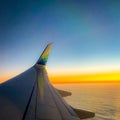 Aircraft wing up in the sky with an amazing unset over the clouds in the background Royalty Free Stock Photo