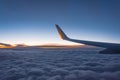 Aircraft wing view from airplane with cloudscape sky after sunset