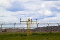 Airfield lights in front of fenced-in airport runway with barbed wire, heading glide path of navigation system of jet aircraft Royalty Free Stock Photo