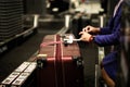 An airline employee is loading suitcases on a baggage delivery conveyor belt at Suvarnabhumi International Airport