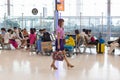 Airline female staff walks by seated Asian tourists inside Suvarnabhumi International AIrport terminal in Bangkok, Thailand