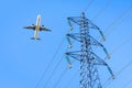 An airliner flying over a high-voltage power line against blue sky Royalty Free Stock Photo