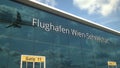 Commercial plane landing reflecting in the windows with Flughafen Wien Schwechat or Vienna Airport text. 3d rendering
