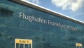 Landing airplane reflects in the modern windows with Flughafen Frankfurt am Main or Frankfurt am Main Airport text. 3d