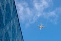 Airplan leaves a trail in the blue sky. Airliner is takking off over the building. White cloud in the blue sky in which Royalty Free Stock Photo