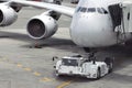 Airplane on airport runway with pushback tractor