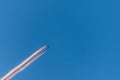 Airplane in a blue cloudless sky with colored colorful contrails without clouds during sunset and golden hour, Germany