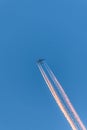 Airplane in a blue cloudless sky with colored colorful contrails without clouds during sunset and golden hour, Germany