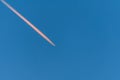 Airplane in a blue cloudless sky with colored colorful contrails without clouds during sunset and golden hour, Germany