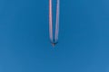 Airplane in a blue cloudless sky with colored colorful contrails without clouds during sunset and golden hour, Germany