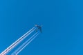 Airplane in a blue cloudless sky with colored colorful contrails without clouds during sunset and golden hour, Germany