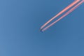 Airplane in a blue cloudless sky with colored colorful contrails without clouds during sunset and golden hour, Germany