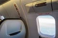 Airplane cabin passenger seat next to emergency exit with signs and instructive writings