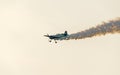 Airplane with colored trace smoke flying in the blue clouds sky, stunt aerobatic show, sunset and sun rays