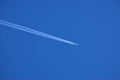 Airplane contrail against clear blue sky background with copyspace. View of a distant passenger jet plane flying on high