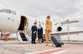 Airplane crew leads woman in yellow clothes inside of a plane Royalty Free Stock Photo