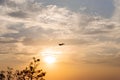 Airplane dark silhouette on orange sunset sky with clouds. Propeller plane outline shape on setting sun background