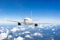 Airplane flies over the summer clouds and the earth`s surface under the blue sky. Royalty Free Stock Photo