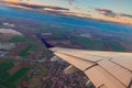 Airplane flight in sunset sky over city and wing of plane. View from the window of the Aircraft. Traveling in air