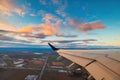 Airplane flight in sunset sky over city and wing of plane. View from the window of the Aircraft. Traveling in air Royalty Free Stock Photo