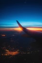 Airplane flight in sunset sky over earth of city light and wing of plane. View from the window of the Aircraft. Traveling in air Royalty Free Stock Photo