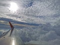 Airplane flight travel. Clouds and sky with sun light view through window of aircraft wing.