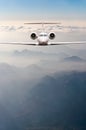 Airplane fly over clouds and Alps mountain on sunset. Front view of a big passenger or cargo aircraft, business jet Royalty Free Stock Photo