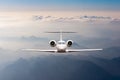 Airplane fly over clouds and Alps mountain on sunset. Front view of a big passenger or cargo aircraft, business jet Royalty Free Stock Photo