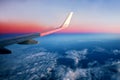 Airplane flying above clouds at pink sunrise Royalty Free Stock Photo