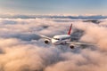 Airplane is flying above the clouds at sunrise in summer Royalty Free Stock Photo