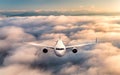 Airplane is flying above the clouds at sunrise in summer Royalty Free Stock Photo