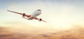 Airplane flying above clouds at sunset Royalty Free Stock Photo