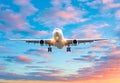 Airplane flying arrival landing on a runway airport in the evening during a bright red sunset cloudscape. Royalty Free Stock Photo