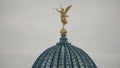 Airplane flying behind golden statue of Pheme or Fama on top of the glass dome of the Dresden Academy of Fine Arts