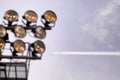 Airplane flying in the blue sky among clouds and sunlight. Against the backdrop of the stadium's spotlights Royalty Free Stock Photo