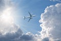 Airplane flying in blue sky, gaining height, sun shine through clouds, bottom view.