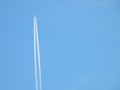 Airplane flying in the clear blue sky and contrail against, Engine exhaust contrails forming behind,  Jet contrails or trails over Royalty Free Stock Photo