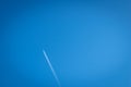 Airplane flying through clear blue sky with vapour trail Royalty Free Stock Photo