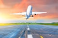 Airplane flying departure take off on a runway airport in the evening during a bright red sunset cloudscape. Royalty Free Stock Photo